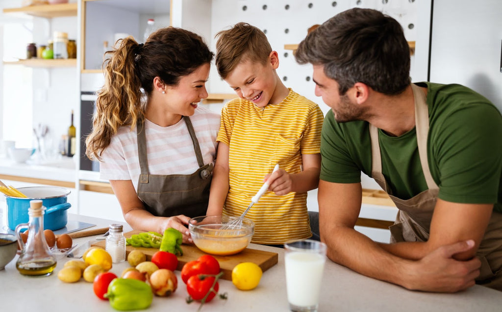 Smiling parents are cooking healthy foods with their child after learning the connection between autism and diet.