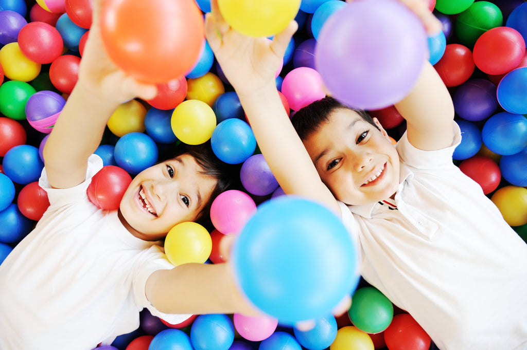 Happy children playing together in ball pit at arcade center