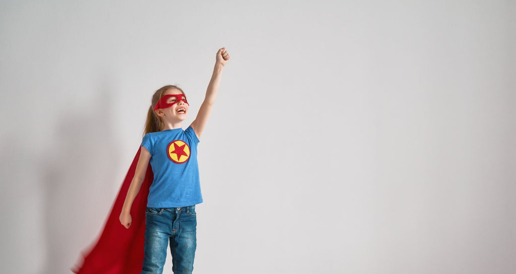 Little girl with tactile defensiveness wearing a red cape pretending to fly like a superhero.